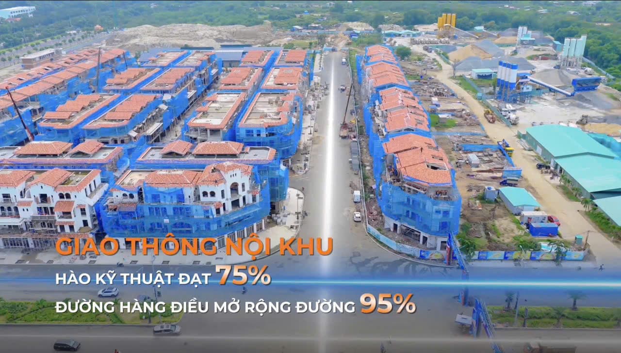 Đại lộ nội khu đã trải nhựa, hai bên là dãy nhà phố phủ lưới xây dựng, trạm trộn bê tông phía xa