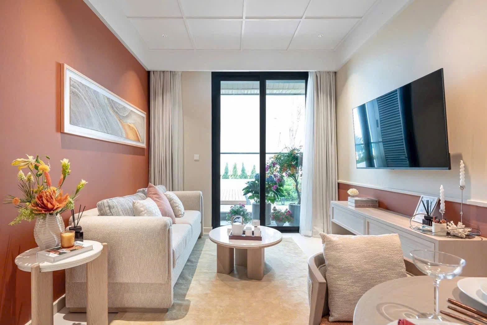Góc rộng phòng khách căn hộ mẫu với tivi treo tường, sofa và cửa kính lớn