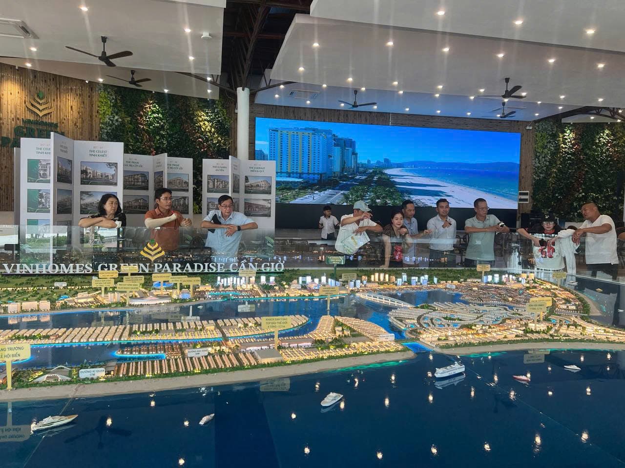 Ảnh chụp khách tham quan đứng quanh sa bàn Vinhomes Green Paradise Cần Giờ tại phòng bán hàng